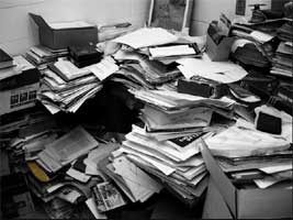 A pile of manuscripts burying just-perceived office furniture