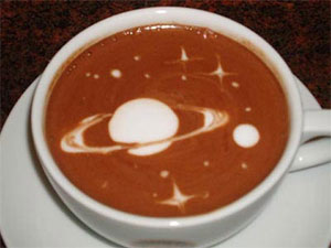 Latte Art A cup of latte with barista art of a ringed planet with a moon surrounded by stars