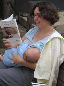 Nursing and reading A pale skinned woman reads 'Breastfeeding: A Parent's Guide' while nursing a baby