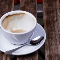 A coffee cup, almost empty, sits on a saucer with a spoon. It's resting on the slats of a wooden table. Image by doug88888 on flickr; used with a Creative Commons license.