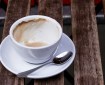 A coffee cup, almost empty, sits on a saucer with a spoon. It's resting on the slats of a wooden table. Image by doug88888 on flickr; used with a Creative Commons license.