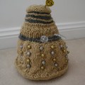 A gold Dalek with silver accents and gold and silver beads as its bobbles. The plunger and ray gun are made of a silver pipecleaner, and the eyestalk out of a gold one.