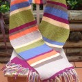 A long and while multicoloured scarf with tassels arranged on a chair in an outdoor setting.