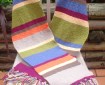 A long and while multicoloured scarf with tassels arranged on a chair in an outdoor setting.