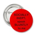 A pinback badge: red background with text saying SOCIALLY INEPT; speak BLUNTLY to me
