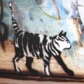 a photo of a stencil-art stripey cat on a brick wall in Newtown