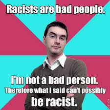 Privilege Denying Dude Is Not A Bad Person Background: 8 piece pie style color split with red and teal alternating. Foreground: White guy with glasses and light shadow wearing a sweat shirt over a button down and short black hair. Has a smug, arrogant facial expression and crossed arms.