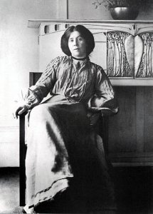 B&W Photo Portrait of Margaret MacDonald, seated in front of a Macintosh-desinged fireplace