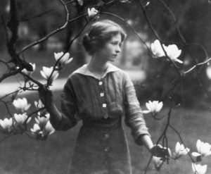 B&W photo of Millay as a young woman in a garden with magnolia blossom