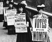 B&W photo of a row of Edwardian women holding signs demanding the vote.