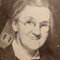 Sepia photo of elderly white woman in round spectacles.