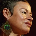 Close up of face of Tina Harrod wearing peacock feather earring.