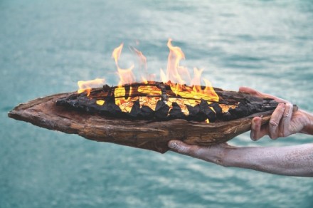 Ceremonial fire on bark plate held over water.