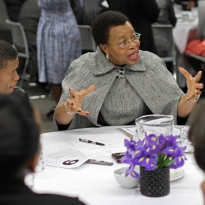 Graça Machel, in grey, speaking while seated at a table.