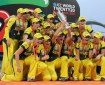A group of jubilant sportswomen in the Australian national colours of green and gold pose for a photo with a championship trophy