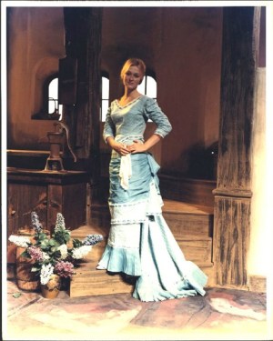 Young white woman in powder blue Victorian dress.