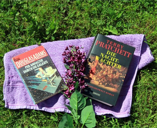 Photograph of German editions of The Hitch Hikers Guide to the Galaxy and Night Watch, together with a lilac towl and a sprig of lilac