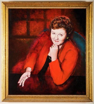 A portrait in oils of a woman wearing a red jacket and a pleasantly determined expression, resting her chin on one hand while gesturing towards the viewer with the other hand. She appears to have just made a persuasive argument.