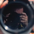 Photograph taken of the photographers reflection in a mirror, mostly what we see is the camera with some fingers and some forehead