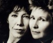 A close-up portrait of two middle-aged pale-skinned women, their faces close and touching